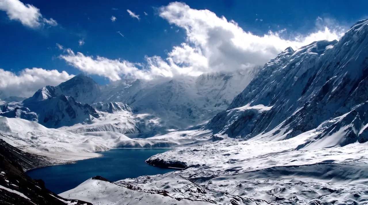 Der tiefblaue Tilicho-See inmitten schneebedeckter Hochgebirgsgipfel